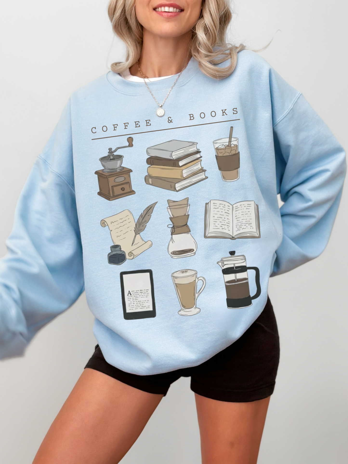 woman modeling light blue reading sweatshirt with cute aesthetic coffee and books design on chest