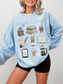 woman modeling light blue reading sweatshirt with cute aesthetic coffee and books design on chest