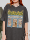 Woman wearing a pepper t shirt with a detailed antique bookstore design featuring open doors, bookshelves, and yellow flowers styled with minimal jewelry indoors
