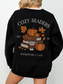 Back of black Cozy Readers crewneck showing large graphic of pumpkins, books, takeaway coffee cup, and leaves. Text reads Cozy Readers Bookstore and Cafe EST 1983.