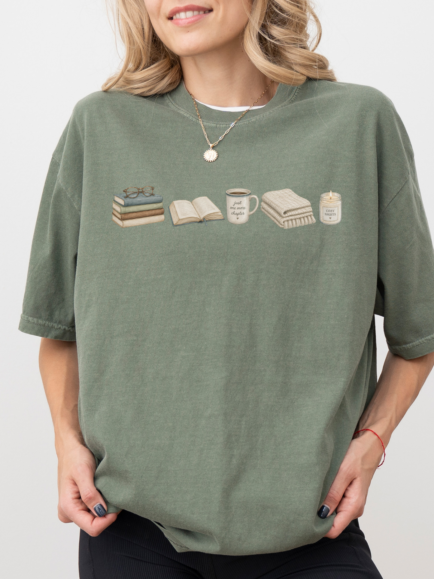 Woman wearing a moss green Comfort Colors book lover shirt with books, coffee mug, blanket and cozy reading candle design