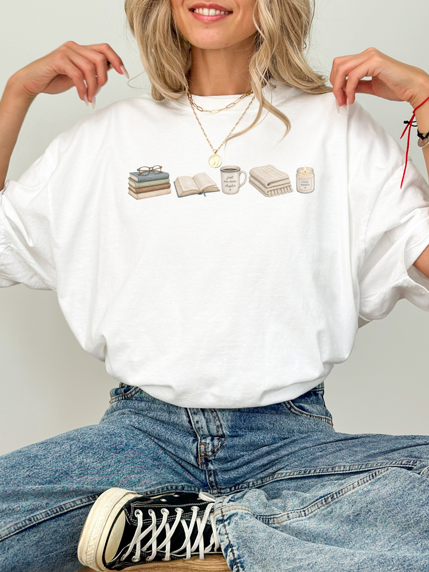 Woman wearing a white book lover t-shirt with books, Just One More Chapter mug, blanket and candle reading design