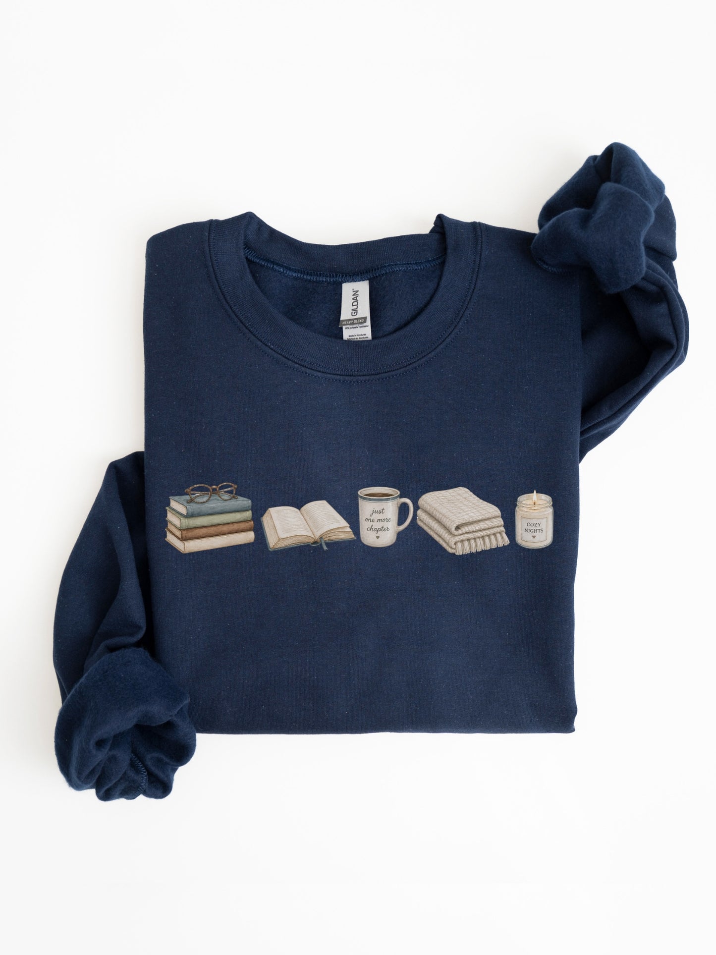 Folded navy Gildan book lover sweatshirt featuring books, Just One More Chapter mug, blanket and candle design