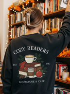 girl standing in a holiday-decorated bookstore wearing a black sweatshirt with a cozy reader holiday graphic on the back