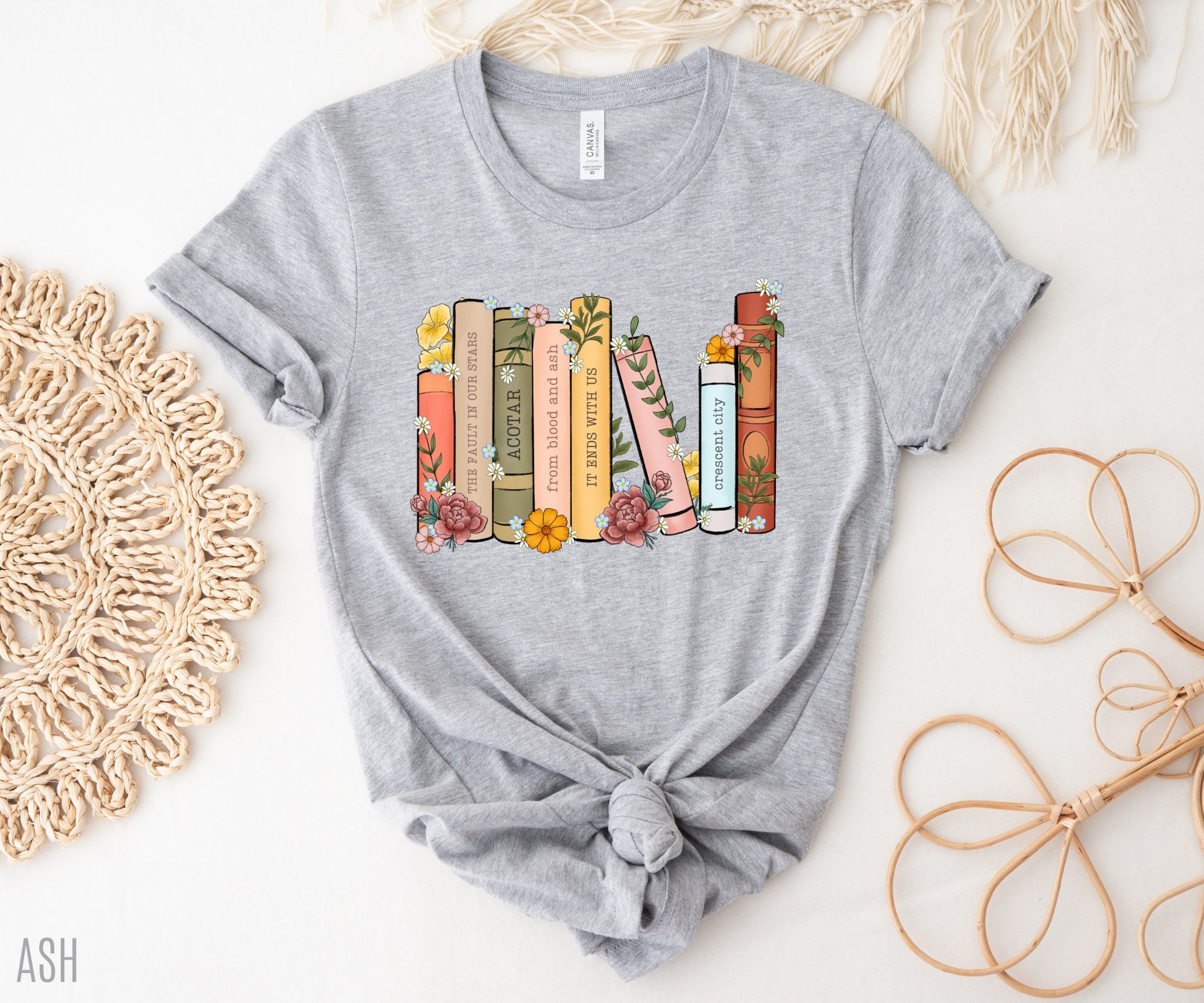 flatlay of athletic heather grey shirt with pastel floral bookshelf design and customizable book spines