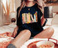 woman sitting on bed wearing black custom bookshelf shirt with cozy bookish aesthetic