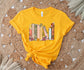 flatlay of gold t-shirt with custom book shelf graphic featuring pastel flowers and titles