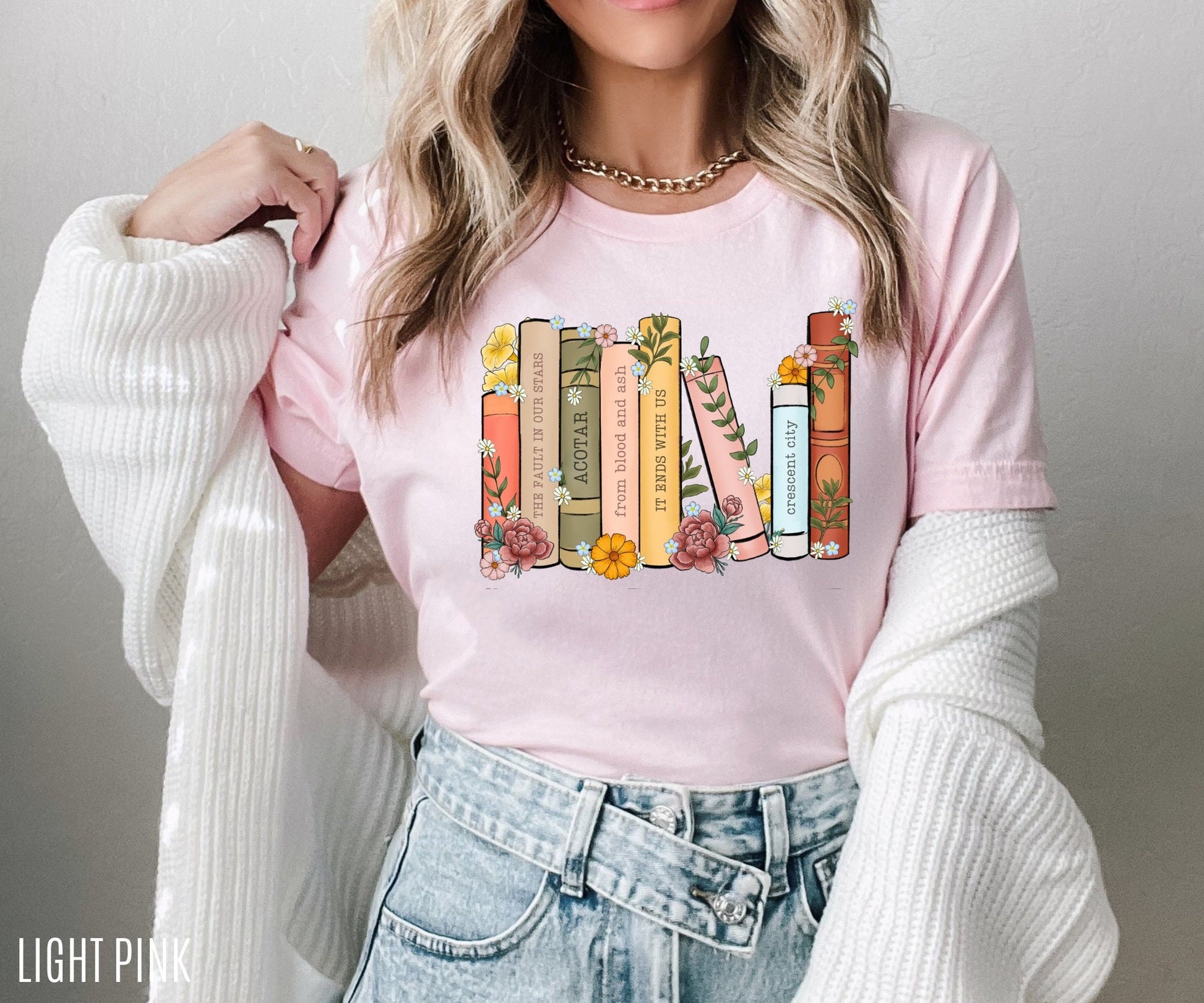 woman wearing light pink floral bookshelf t-shirt with personalized book titles in soft tones