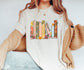 woman in natural t-shirt featuring pastel floral book spines with popular book titles on bookshelf design