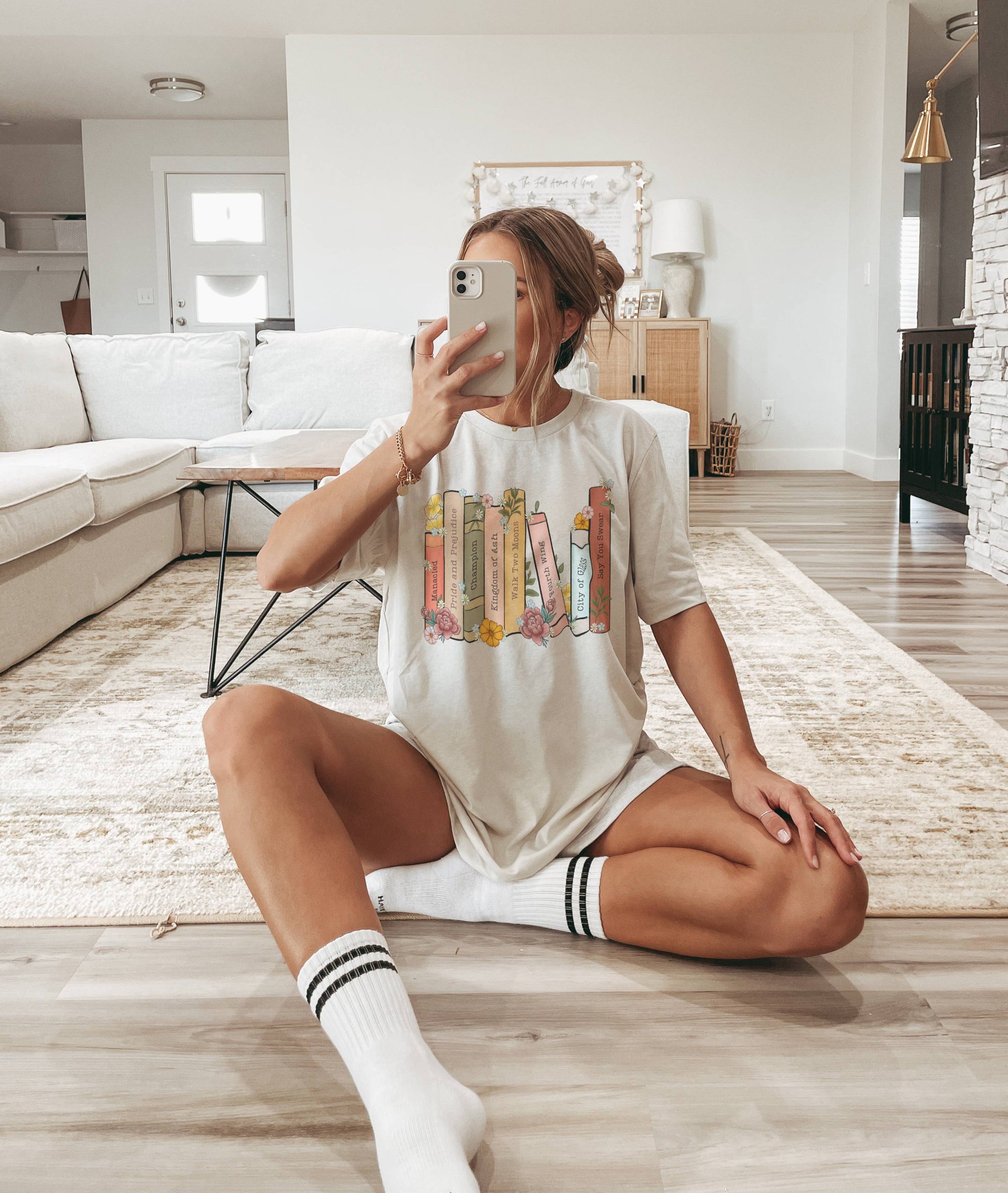 woman sitting on floor in natural custom bookshelf shirt showing pastel floral book spines