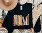 folded black sweatshirt with colorful bookshelf of fantasy and YA titles decorated with flowers