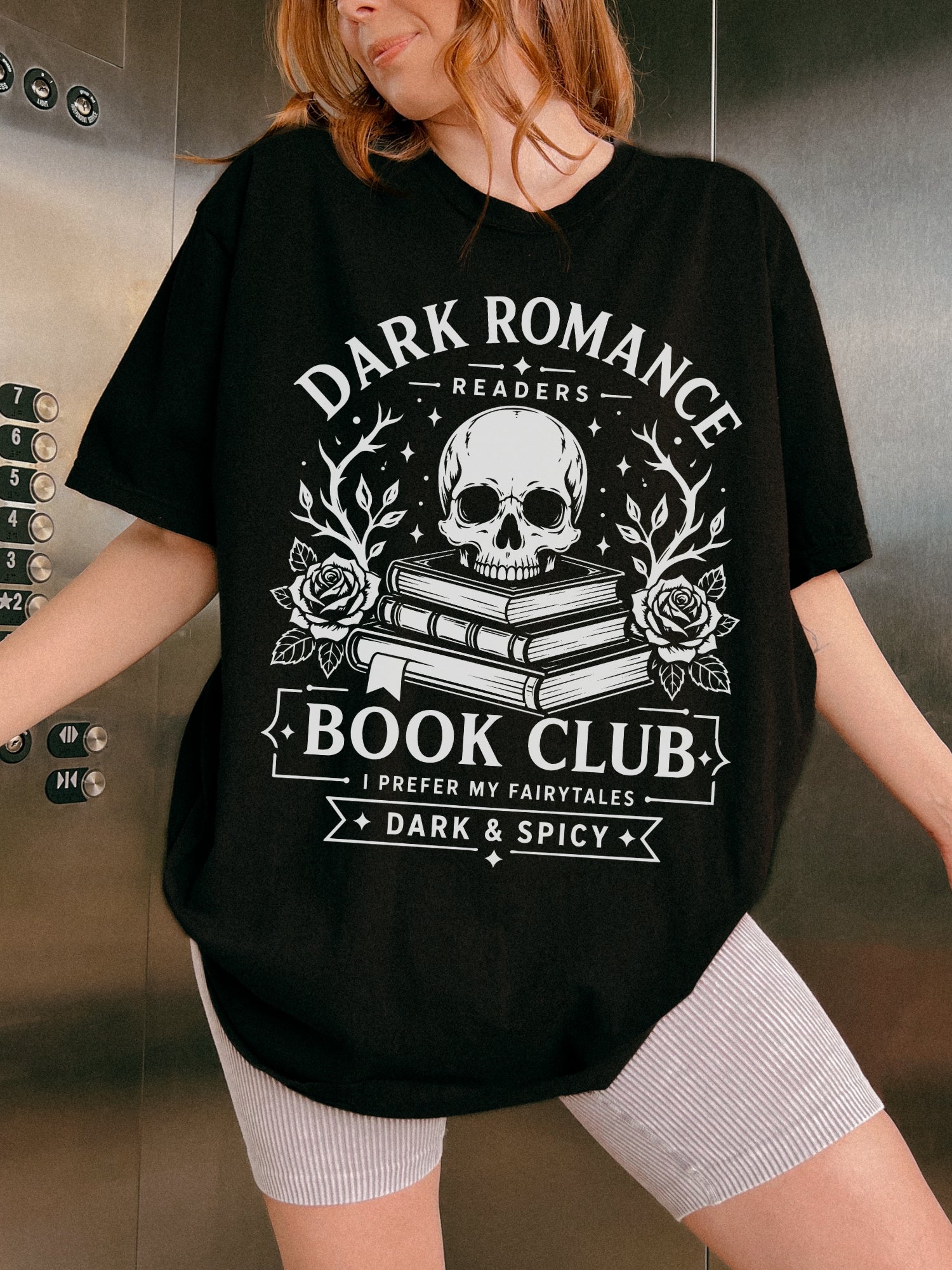 Model wearing a Black Comfort Colors bookish shirt featuring Dark Romance Readers Book Club text with skull, books and roses graphic for romance readers
