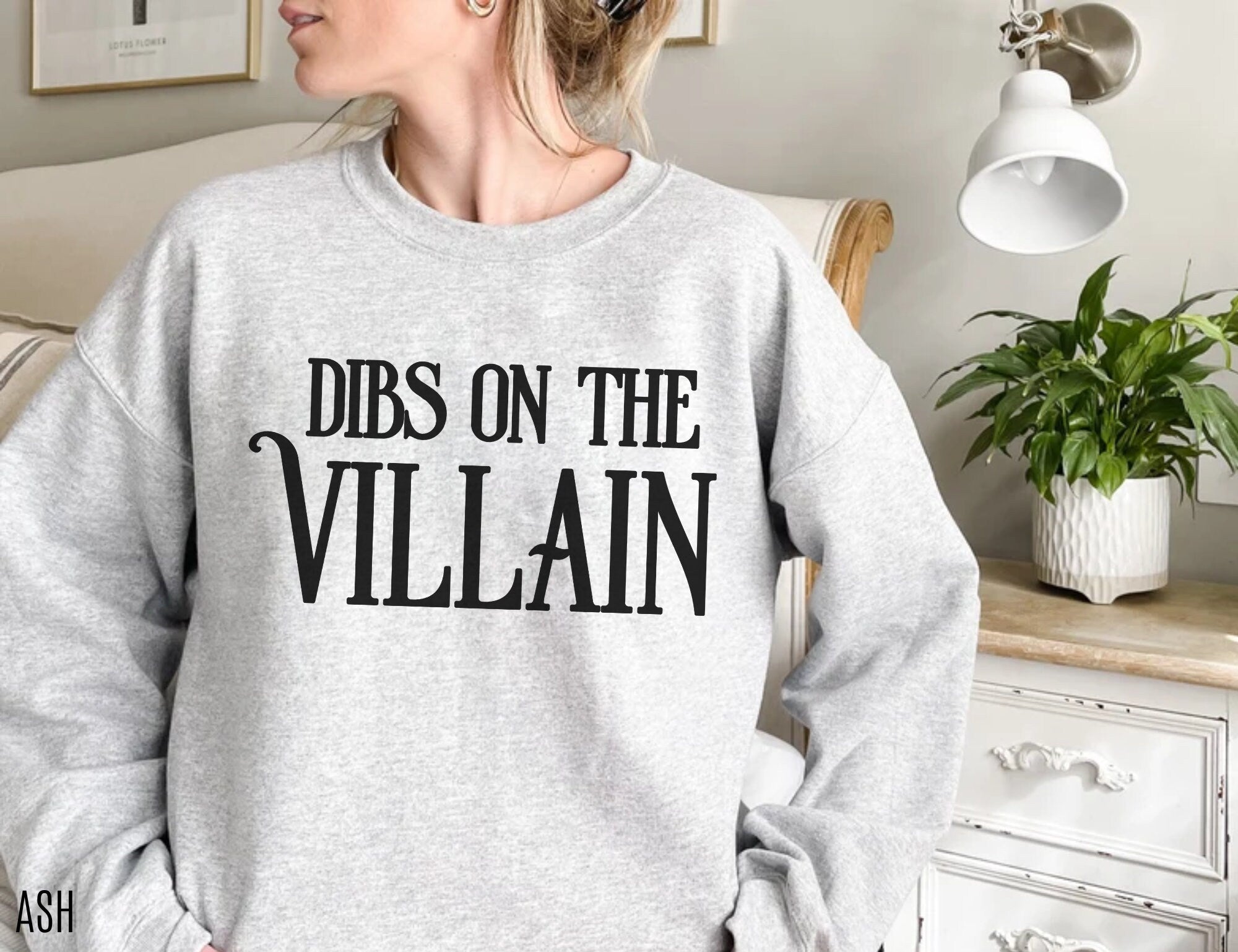 woman wearing ash grey sweatshirt with Dibs on the Villain print in black 
