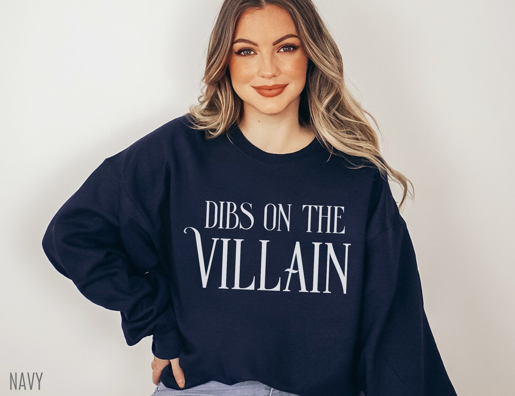 woman posing in navy Dibs on the Villain sweatshirt with soft waves and casual jeans