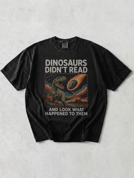 flay lay of a graphite tshirt with a retro graphic that says "dinosaurs didn't read and look what happened to them"