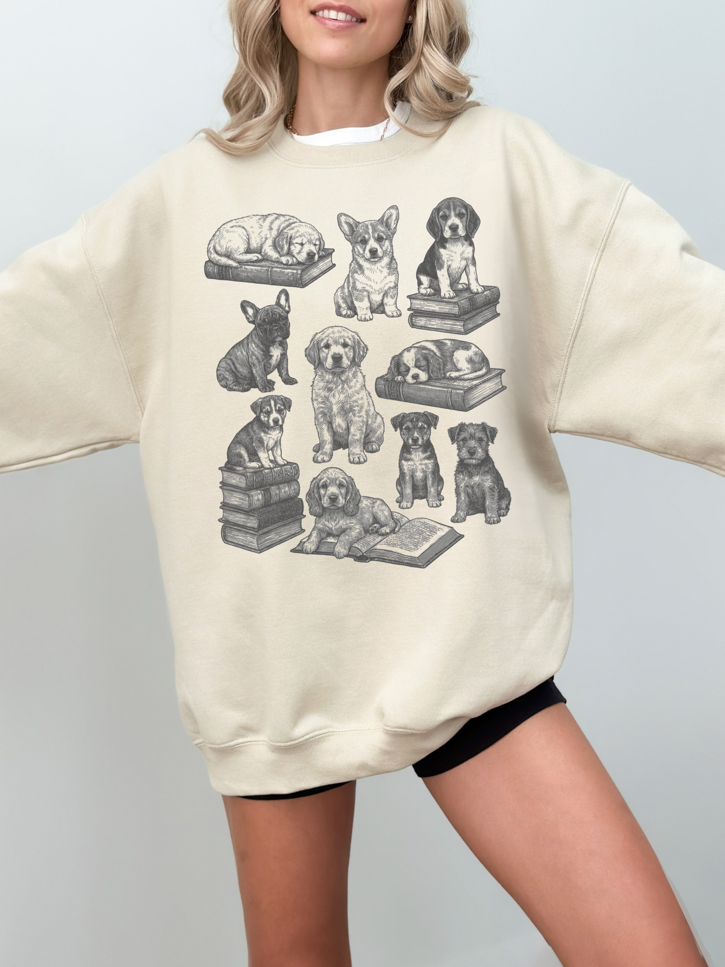 close-up of a sand sweatshirt with sleeping puppies and book stacks printed in a hand-drawn style