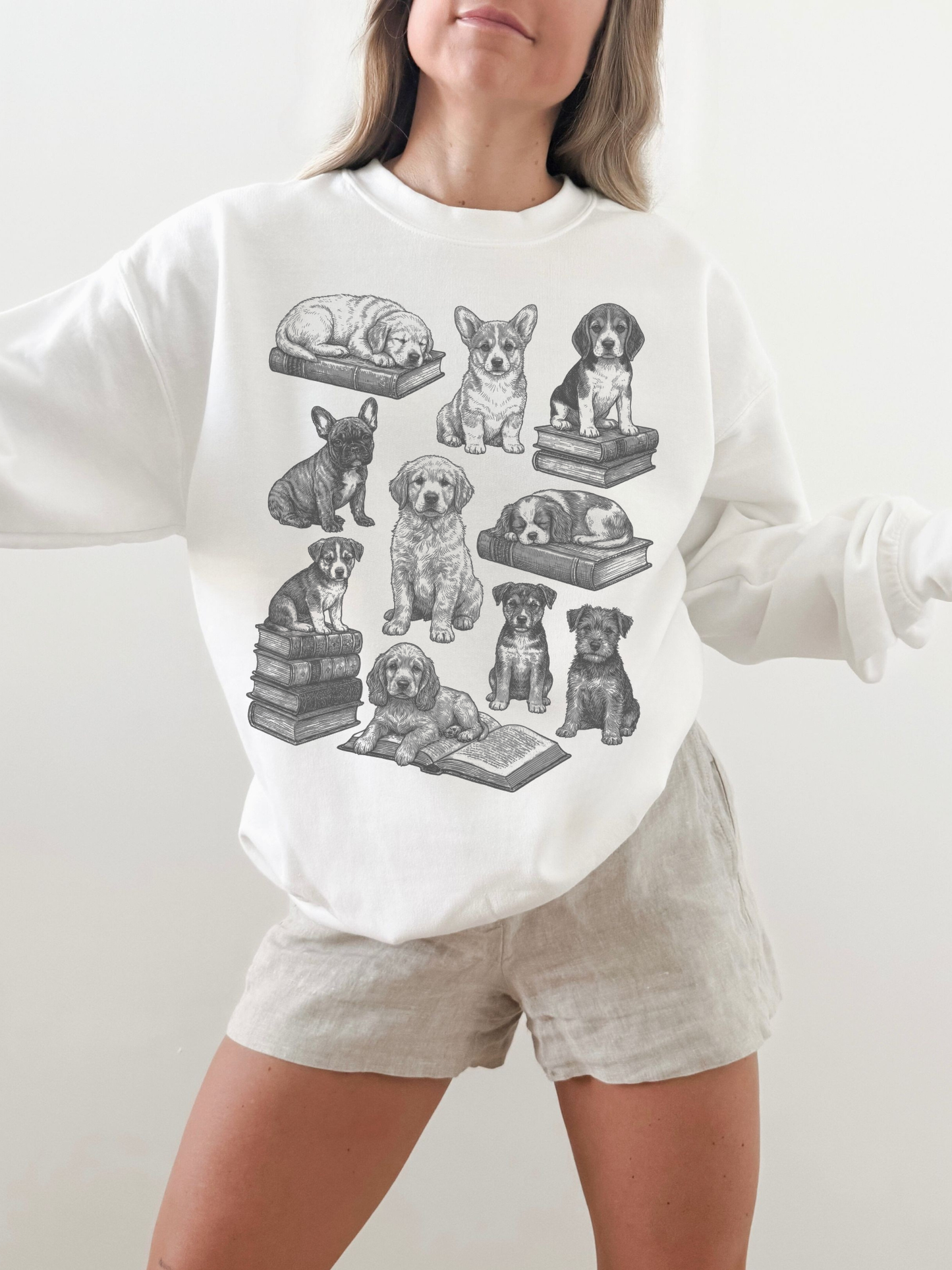 woman wearing a white sweatshirt featuring vintage dog illustrations with books, posing with relaxed arms