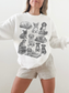 woman wearing a white sweatshirt featuring vintage dog illustrations with books, posing with relaxed arms