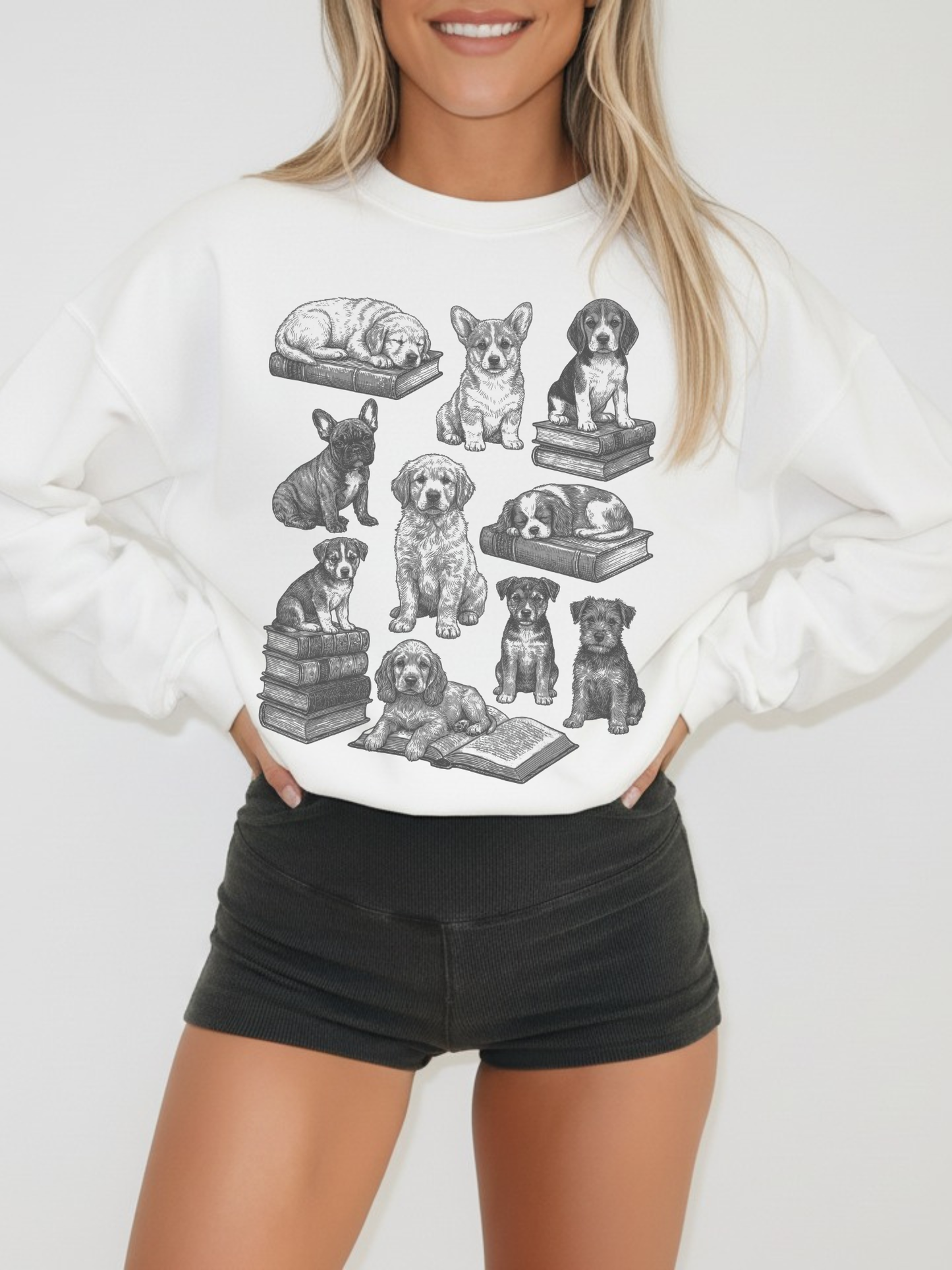 smiling model in white dog and books sweatshirt with corgi, retriever, and bulldog illustrations stacked on classic books