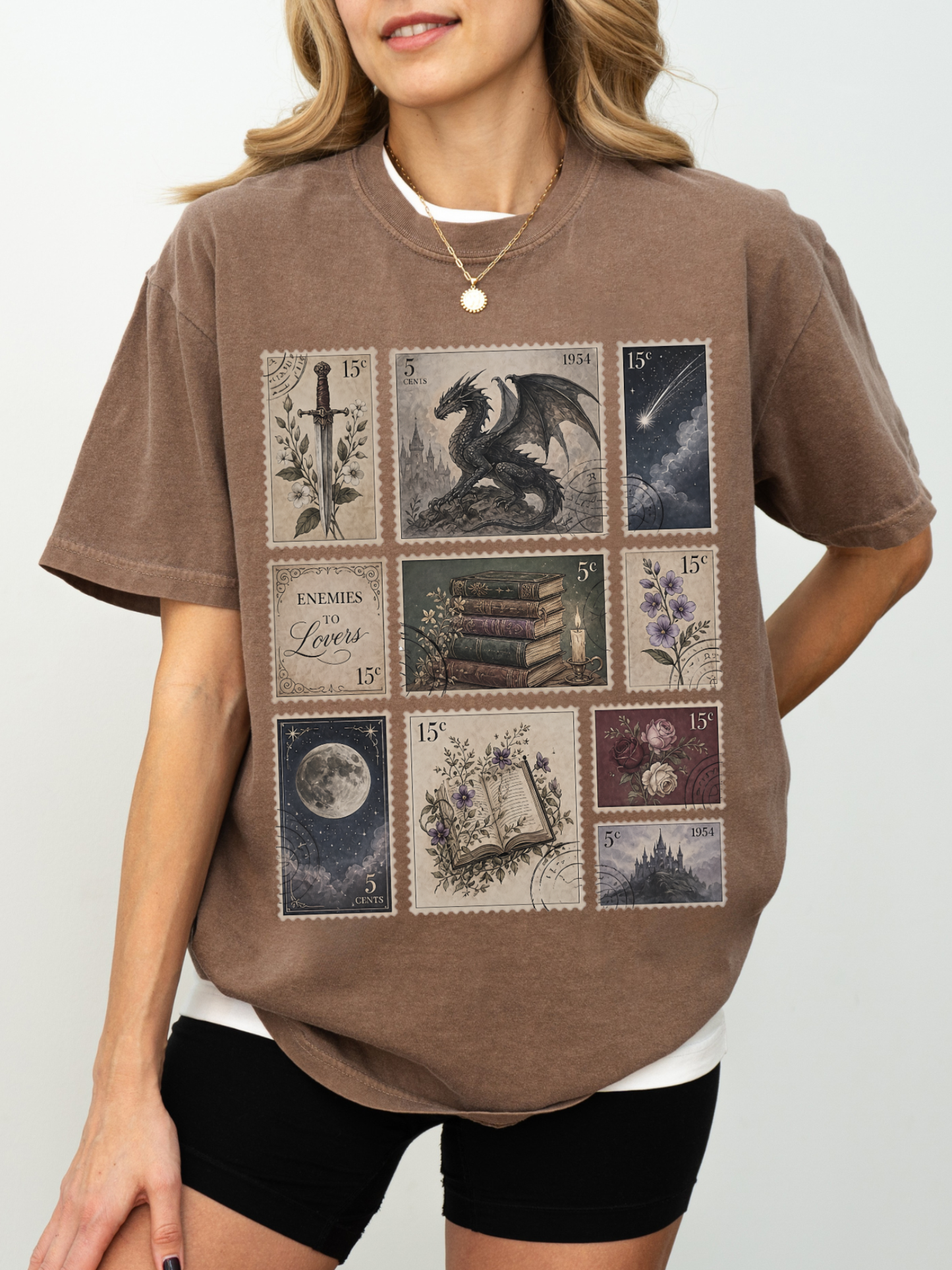 Woman wearing espresso fantasy reader aesthetic t shirt featuring vintage postage stamp collage with dragon books moon floral artwork castle and enemies to lovers inspired design