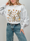 Light gray sweatshirt with cozy autumn bookish skeletons design, worn by a woman standing with hand on hip and smiling