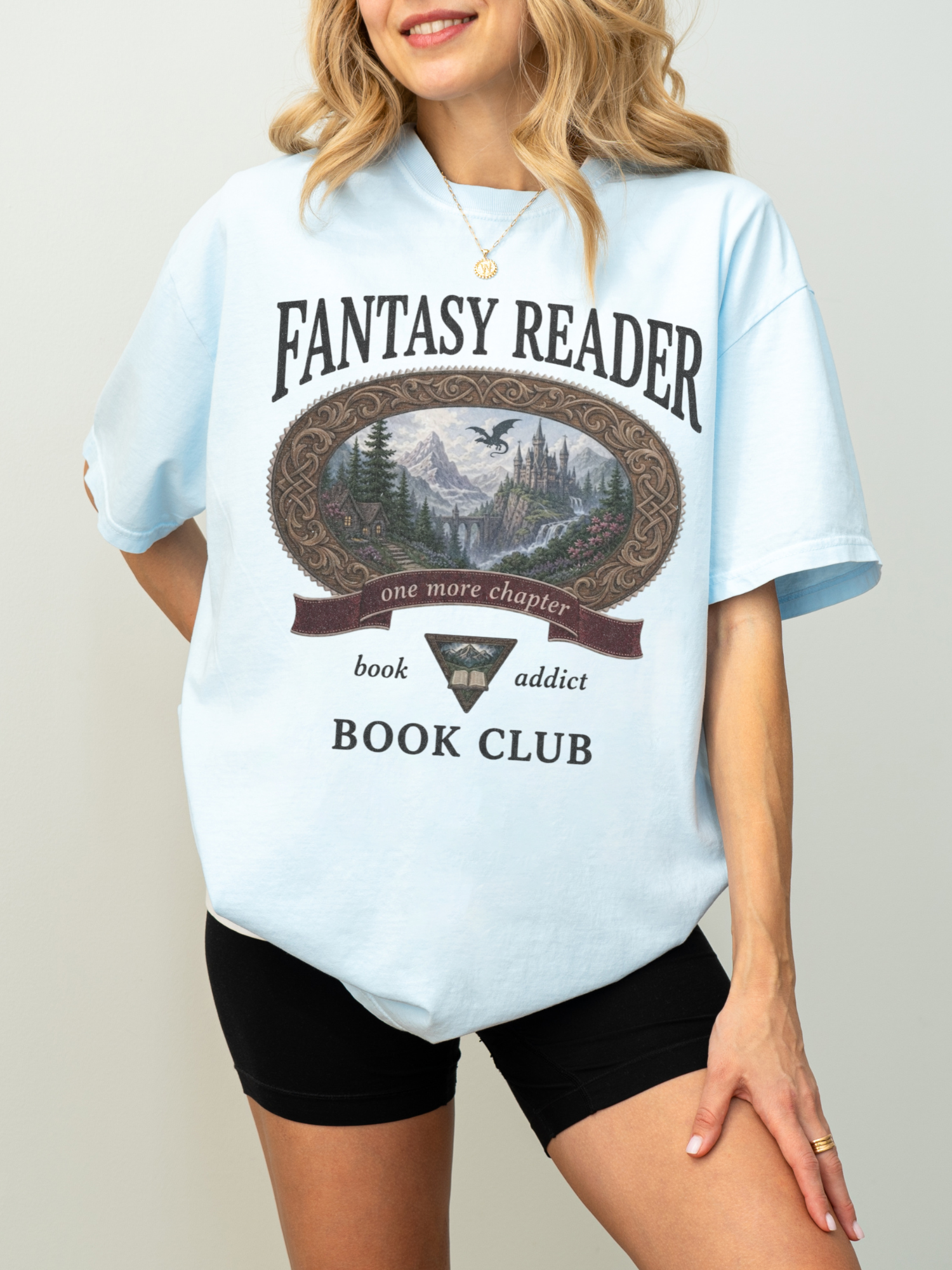 woman wearing a chambray Comfort Colors Fantasy Reader Book Club shirt featuring a castle, dragon, mountains, and fantasy reader graphic for bookworms