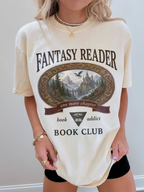 woman wearing an ivory Comfort Colors Fantasy Reader Book Club shirt with fantasy landscape artwork, dragon, castle, and book addict graphic for romantasy fans