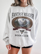 woman wearing an ash Fantasy Reader Book Club sweatshirt featuring a fantasy castle scene, dragon artwork, mountains, and one more chapter design for bookworms and fantasy readers