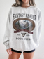 woman wearing an ash Fantasy Reader Book Club sweatshirt featuring a fantasy castle scene, dragon artwork, mountains, and one more chapter design for bookworms and fantasy readers
