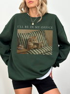 Dark green oversized sweatshirt with Ill be in my office text and a cozy cat reading in bed illustration. Styled as a relaxed casual outfit for readers, introverts, and cat lovers who enjoy cozy apparel.