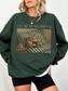 Dark green oversized sweatshirt with Ill be in my office text and a cozy cat reading in bed illustration. Styled as a relaxed casual outfit for readers, introverts, and cat lovers who enjoy cozy apparel.
