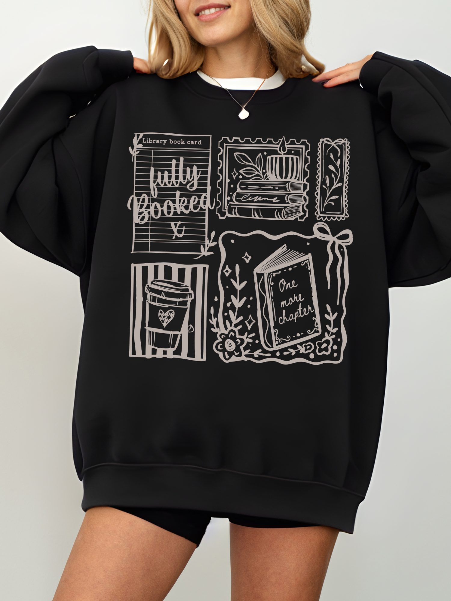 woman wearing black fully booked book lover sweatshirt with vintage reading illustrations cozy oversized fit aesthetic