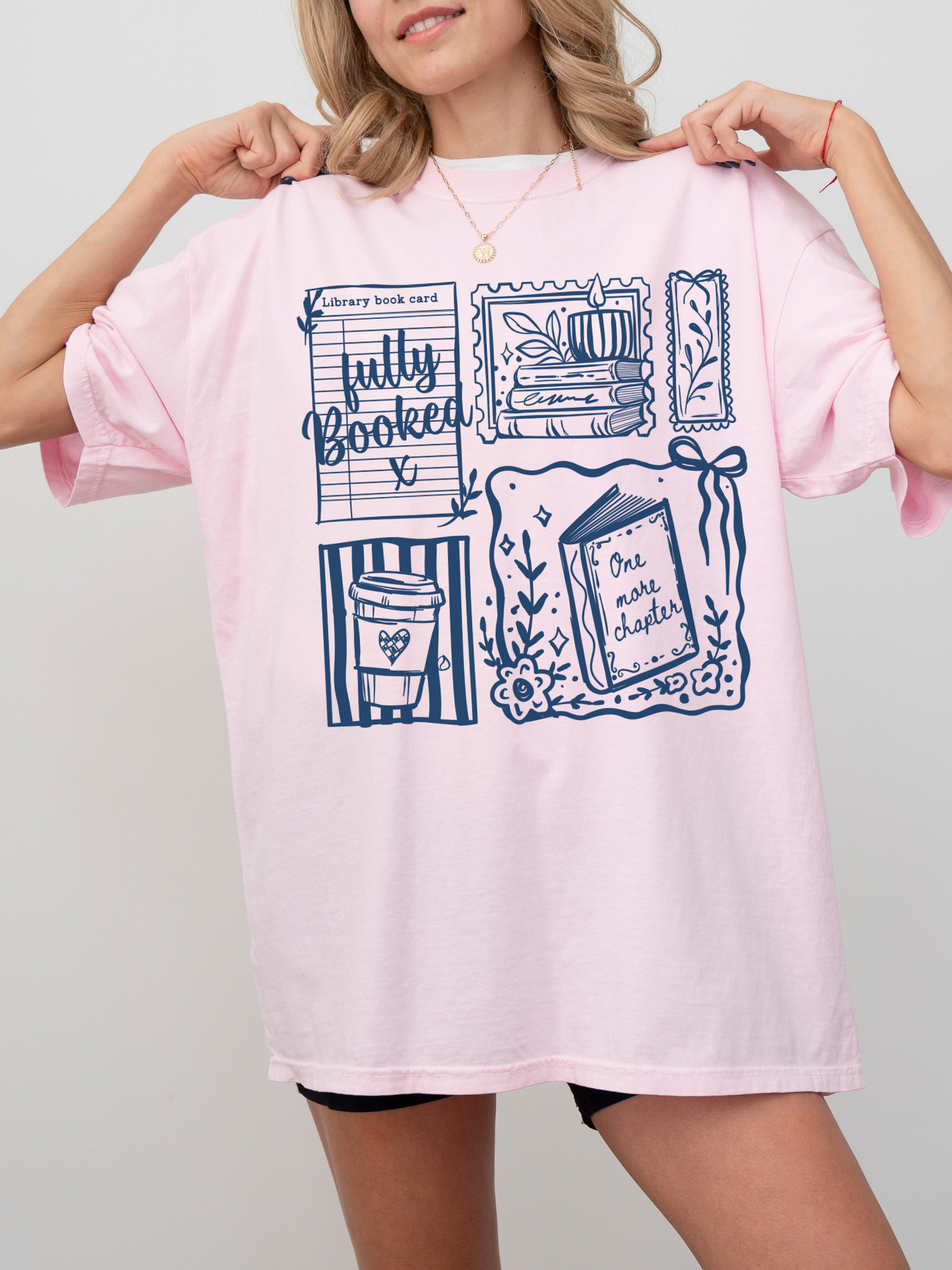 woman wearing oversized pink fully booked book lover t shirt with library card and reading themed illustrations casual outfit