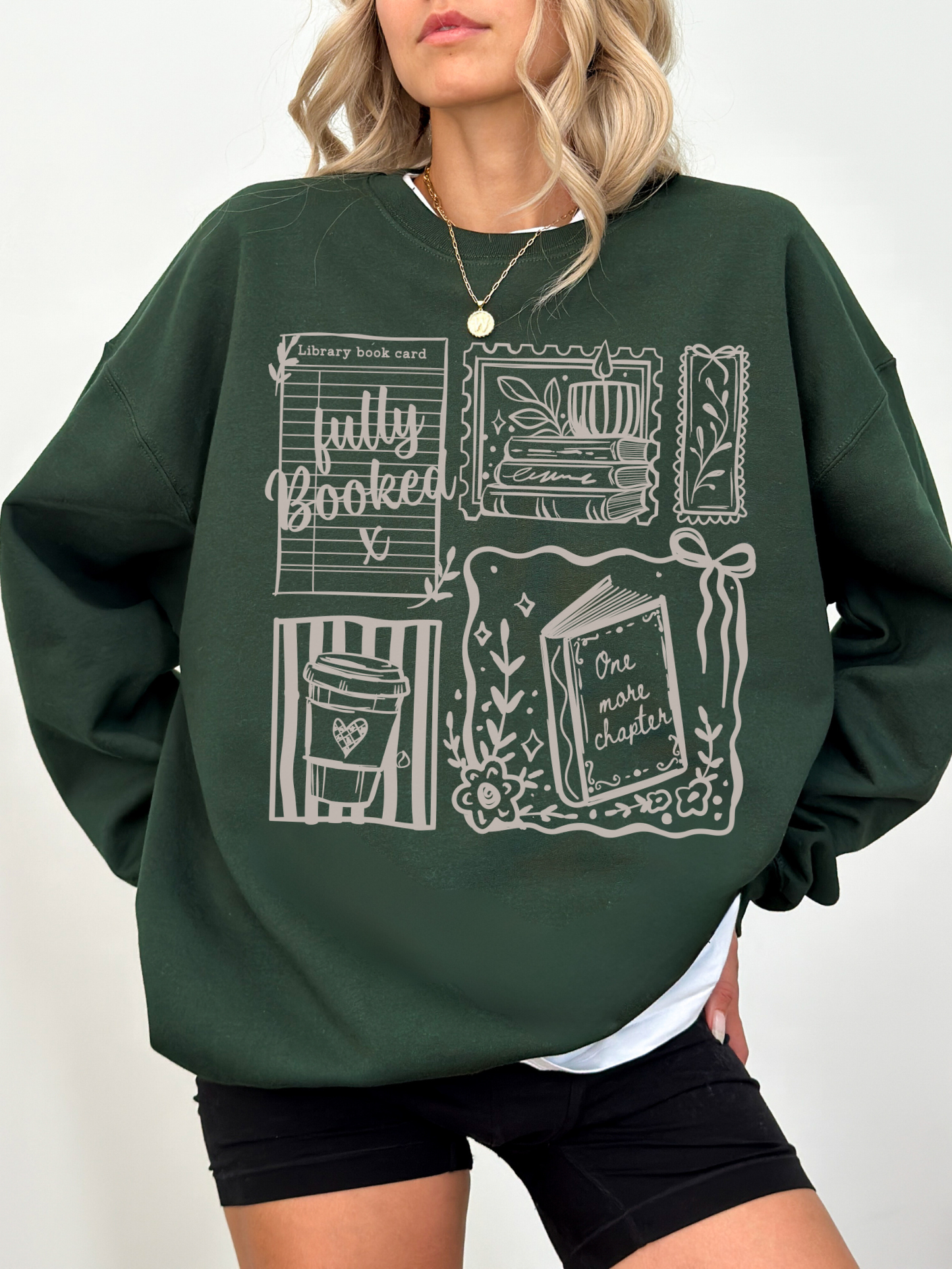 woman wearing dark green fully booked book lover sweatshirt with vintage reading illustrations relaxed oversized cozy outfit