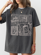 woman wearing pepper fully booked shirt with vintage style book lover illustrations including library card books and coffee cup