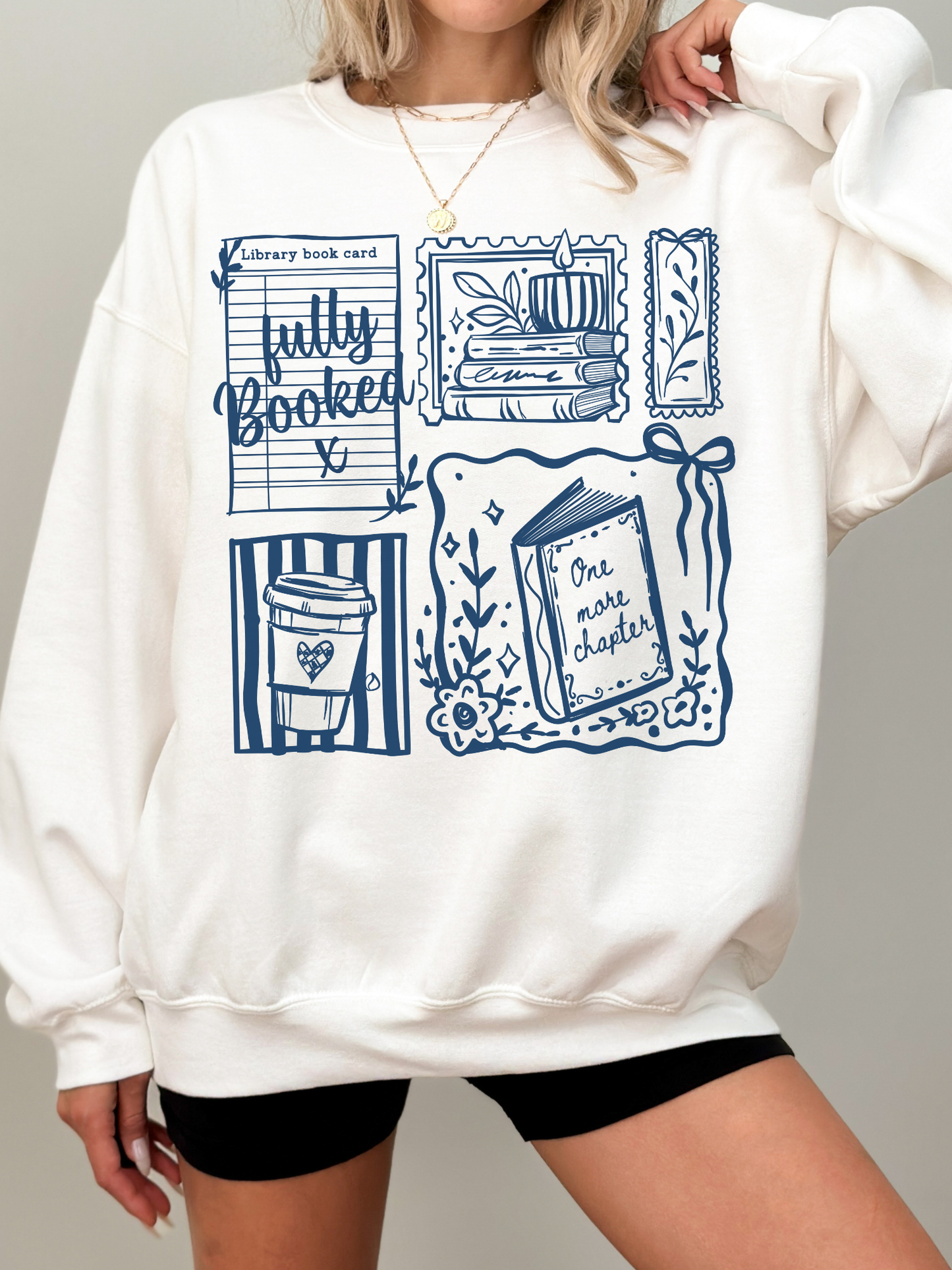 white fully booked book lover sweatshirt with blue reading themed illustrations including books coffee and library card cozy outfit