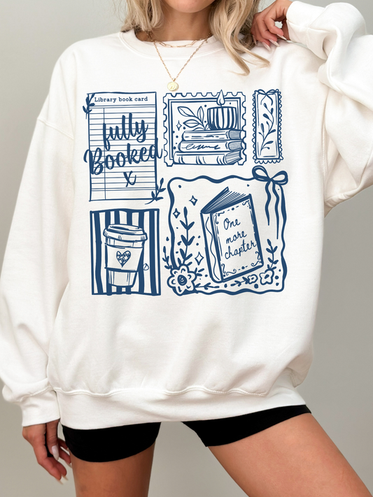white fully booked book lover sweatshirt with blue reading themed illustrations including books coffee and library card cozy outfit