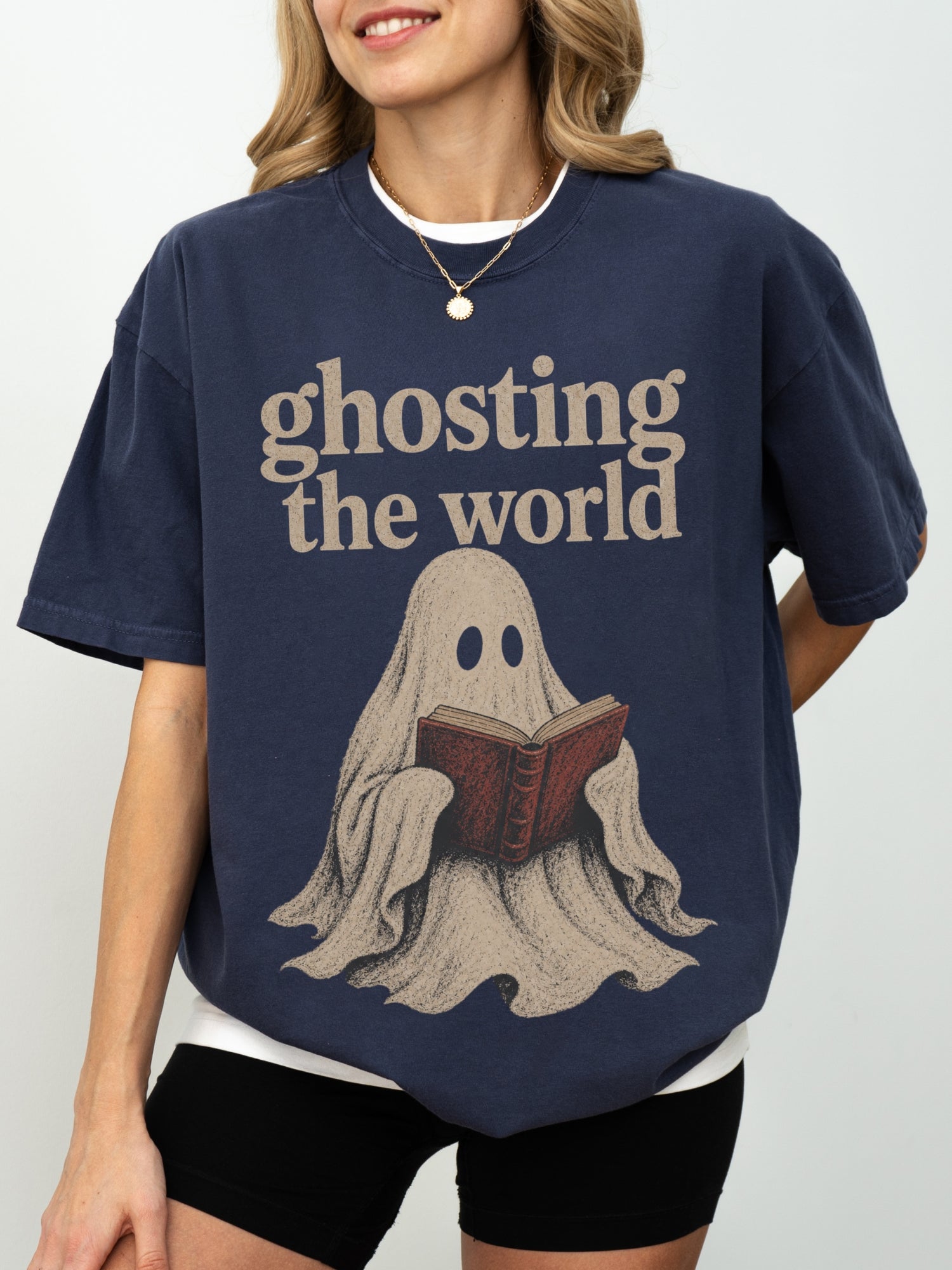 Model wearing a Navy Comfort Colors bookish shirt with Ghosting the World quote and vintage ghost reading a book graphic