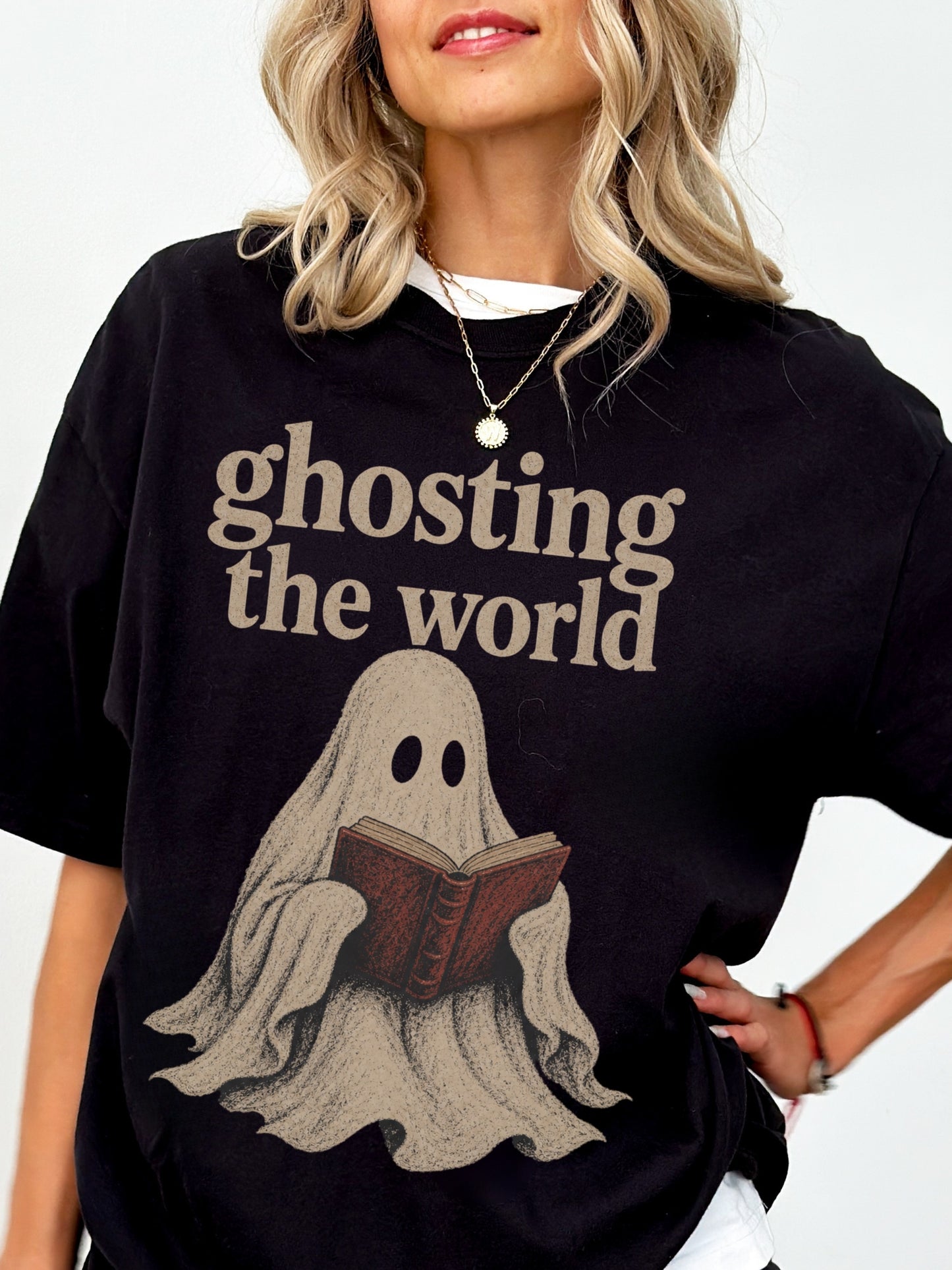 Model wearing a Black Comfort Colors bookish shirt featuring Ghosting the World text and a vintage ghost reading a red book design.
