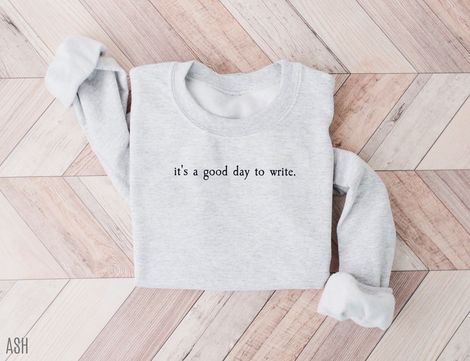 folded ash grey sweatshirt with minimalist it's a good day to write text on wood background