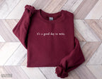 folded maroon sweatshirt that says it's a good day to write in a simple font on wood background