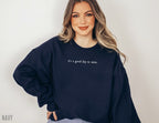 woman wearing navy sweatshirt with simple it's a good day to write design and smiling