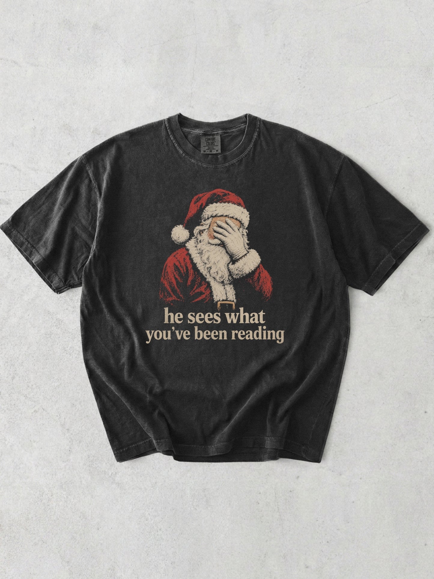 Graphite Comfort Colors shirt featuring vintage Santa covering his eyes with he sees what you’ve been reading text, a funny Christmas bookish shirt for readers and book lovers