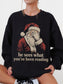 Black Gildan sweatshirt featuring vintage Santa covering his eyes with the funny bookish phrase he sees what you’ve been reading, a Christmas sweatshirt for readers and book lovers