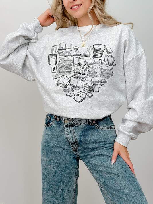 woman wearing ash sweatshirt with black book heart design and high-waisted jeans