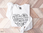 folded white sweatshirt with black book heart design placed on chevron wood background