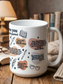 White I Love You in Book Quotes coffee mug styled on wooden table with stacked books and warm lamp light featuring romance novel quotes and illustrated bookish icons