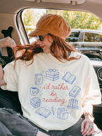 woman sitting in car wearing oversized natural cream bookish graphic shirt with id rather be reading design and illustrated books coffee mug and reading icons