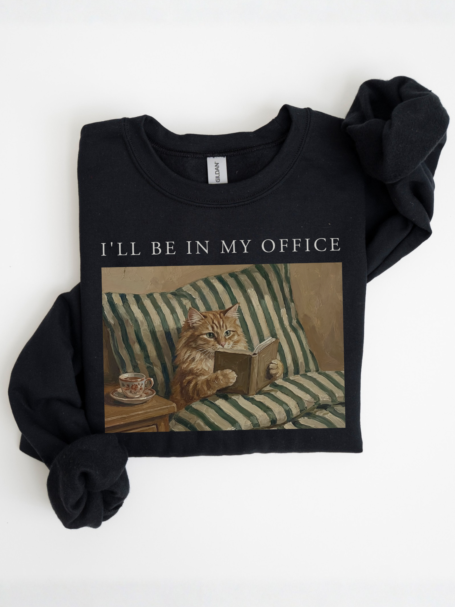 folded black sweatshirt with ill be in my office text and vintage cat reading a book on couch illustration cozy book lover aesthetic