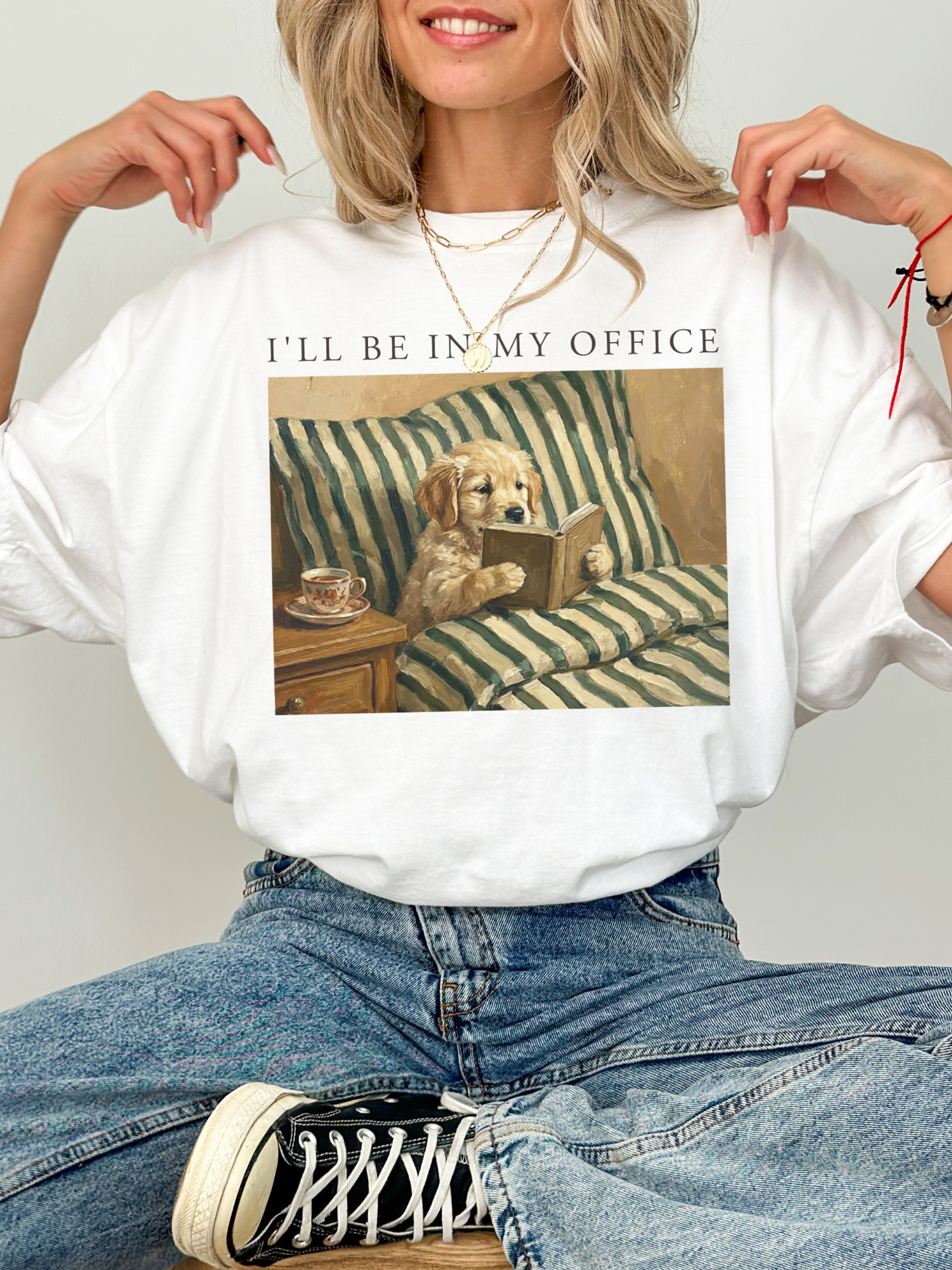 white oversized t shirt styled on model with dog reading book artwork and ill be in my office text cozy reader outfit aesthetic with jeans